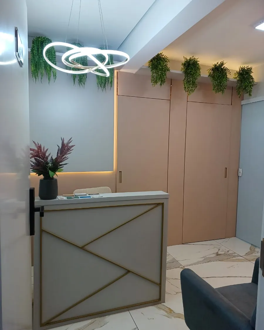 Recepção da Clínica Moriá, com balcão em detalhes dourados e plantas